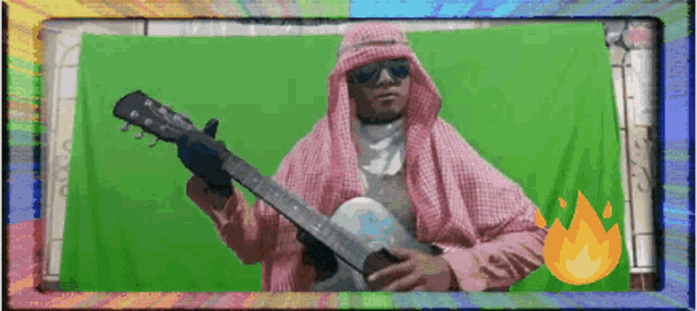 a man in a pink scarf is holding a guitar