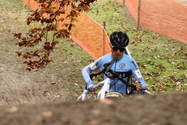 a man wearing a blue shirt that says ' depa ax ' on it is riding a bike