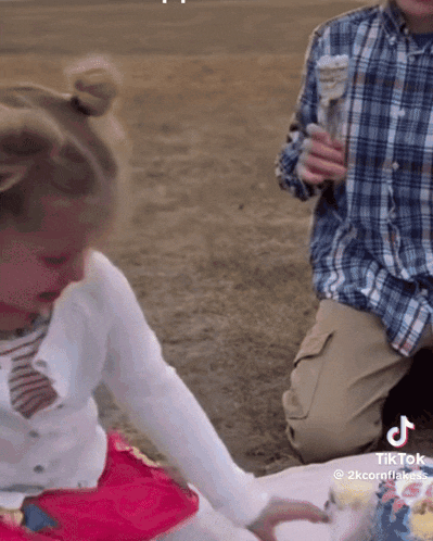 a little girl is playing with a cake and a man is holding an ice cream cone