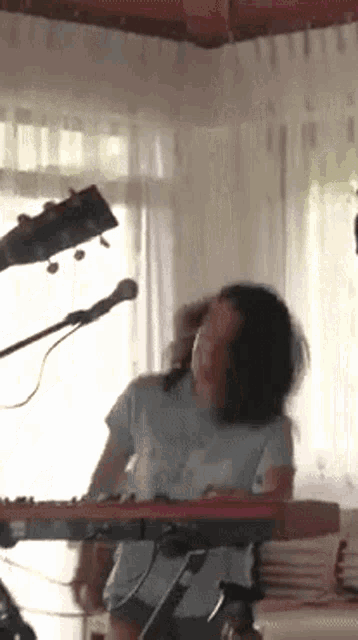 a woman playing a keyboard in front of a microphone