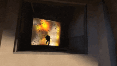 a silhouette of a person walking in front of a screen