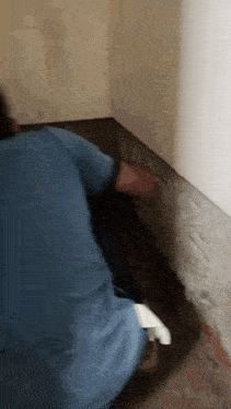 a man in a blue shirt is kneeling down in a room