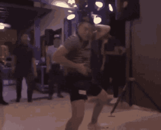 a blurry picture of a man dancing in a room with people standing around