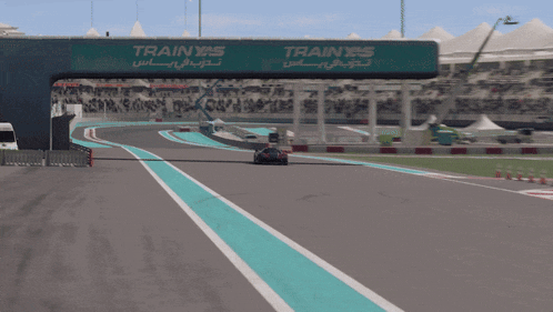 a race car is going down a track with a train sign in the background