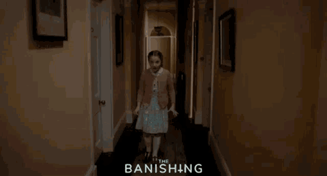 a woman in a yellow shirt is standing in a hallway with the words the banishing on the bottom