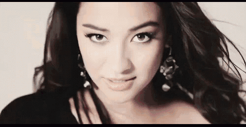 a close up of a woman 's face with her hair blowing in the wind and looking at the camera .