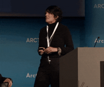 a woman stands at a podium with a name tag that says arctic on it