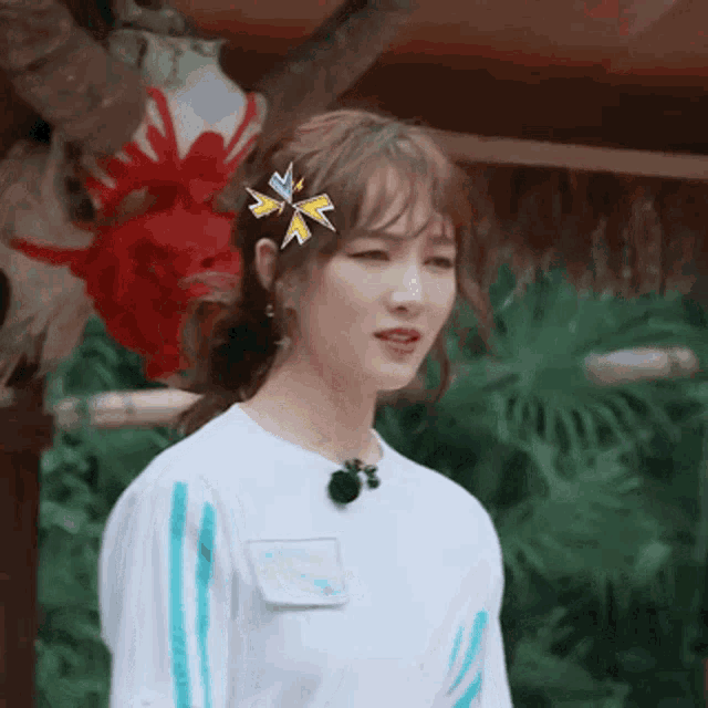 a woman with a flower in her hair is wearing a white shirt with blue stripes on the sleeves