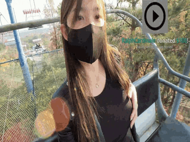 a woman wearing a mask is riding a ferris wheel with a play button in the corner