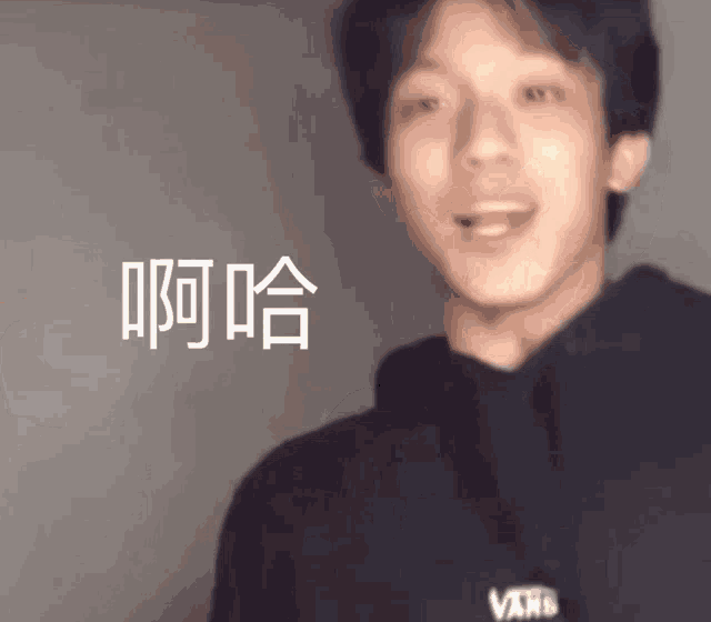 a young man wearing a black vans hoodie is making a funny face with his mouth open .