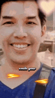 a man in a blue shirt smiles with the words smile your written on his neck