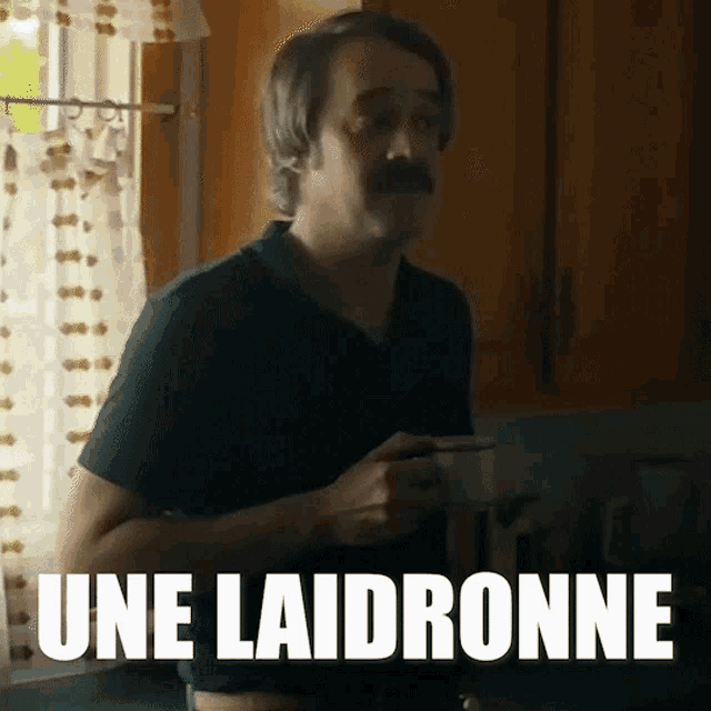 a man with a mustache is holding a cup of coffee in a kitchen with the words une laidronne above him