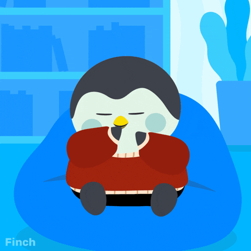 a penguin wearing a red sweater is sitting on a bean bag chair