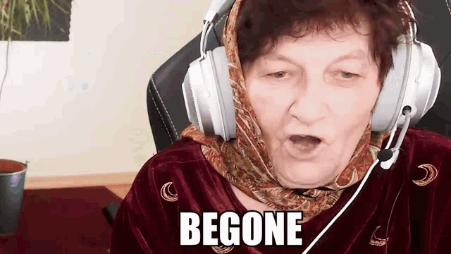 an elderly woman wearing headphones and a head scarf says begone