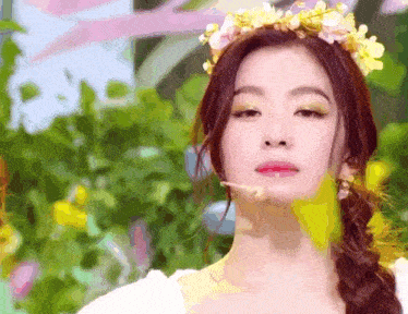 a woman with a flower crown on her head looks at the camera