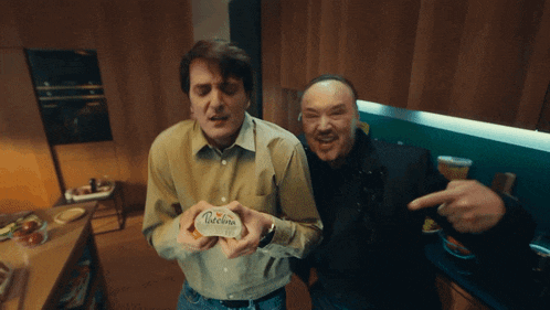 two men are standing in a kitchen one is holding a piece of paper that says receima