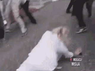 a woman in a white dress is laying on the ground in a crowd .
