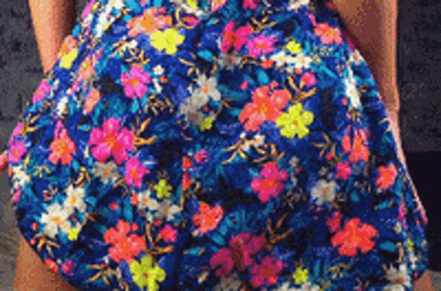 a woman in a blue floral dress is standing with her hands in her pockets