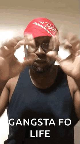 a man wearing glasses , a red hat , and a bandana is making a funny face .