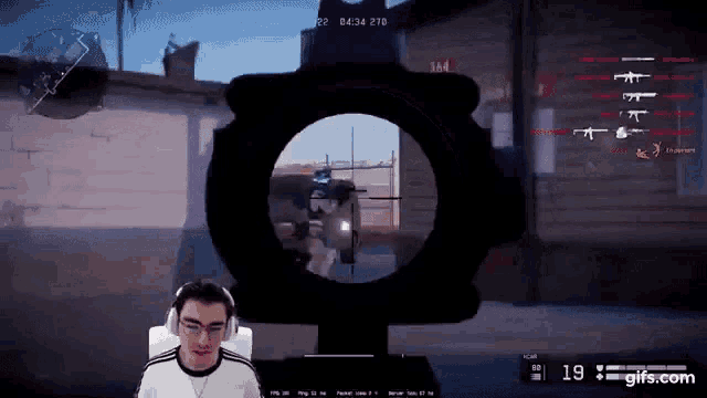 a man wearing headphones is playing a video game with a sniper scope