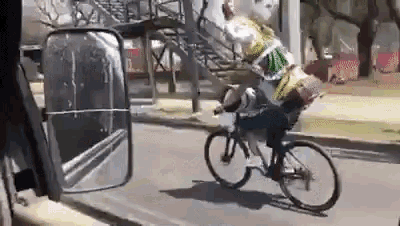 a man is riding a bicycle down a street with a bag on the back .
