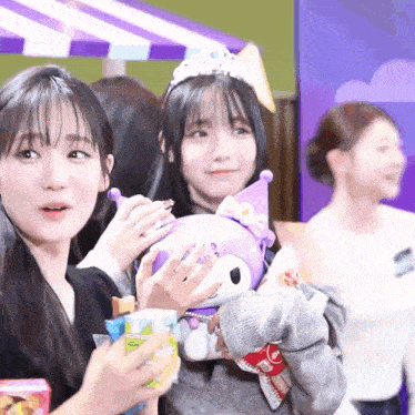 a girl with a crown on her head is holding a purple stuffed animal