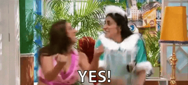 a couple of women are standing next to each other in a room and one of them is saying yes .
