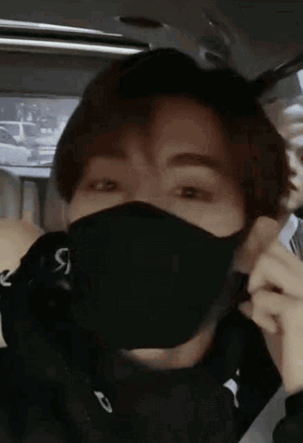 a close up of a person wearing a black mask in a car .