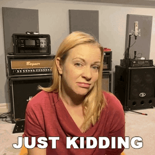 a woman in a red shirt is making a funny face and the words just kidding are above her