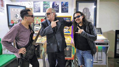 three men are posing in front of a pinball machine that says wulfizer