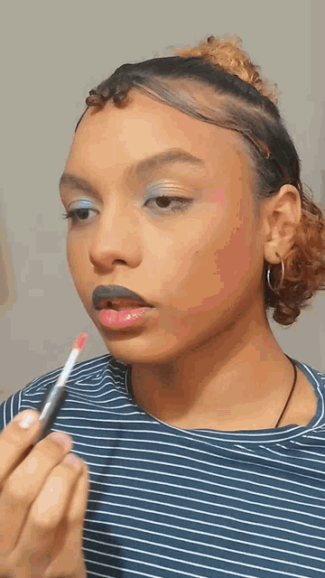 a young girl is applying lipstick to her lips