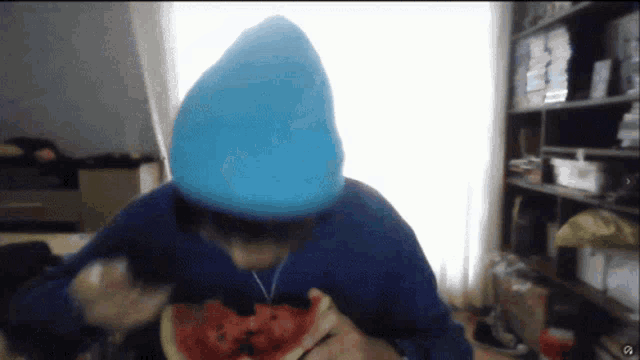 a person wearing a blue hat eating a watermelon