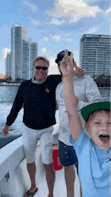 two men and a boy are on a boat and the boy is wearing a hat that says ' miami ' on it