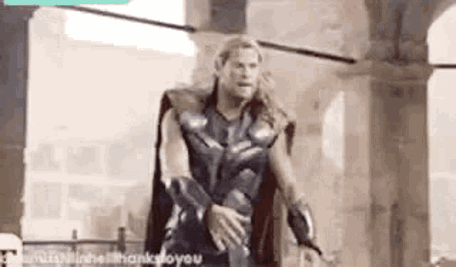 a man in a superhero costume is standing in front of a building in a hallway .