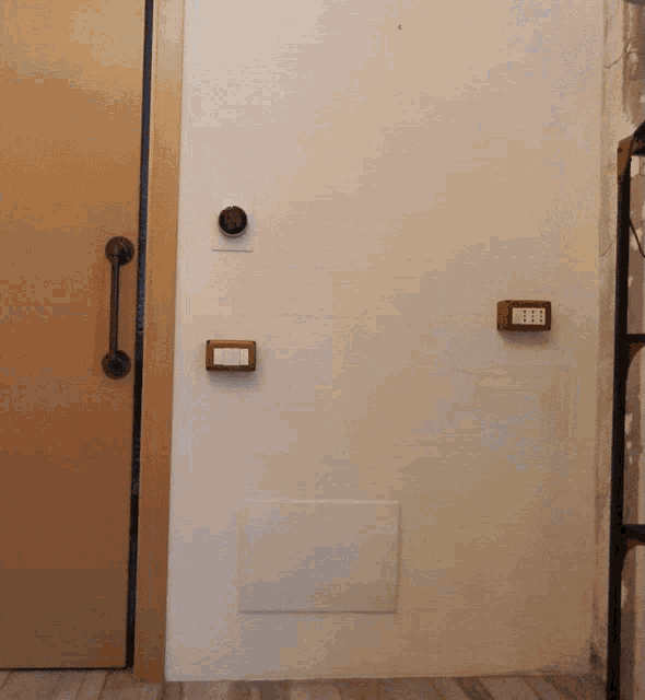 a white wall with a wooden door and two electrical boxes on it