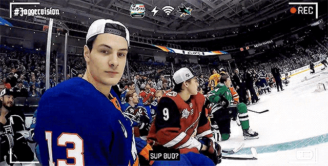 a hockey player with the number 13 on his jersey is sitting in the stands at a game .