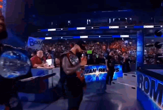 roman reigns is standing in front of a crowd at a wrestling event