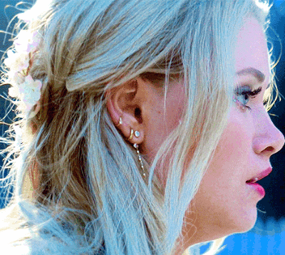 a close up of a woman 's face with blonde hair and earrings