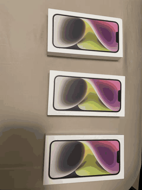 three boxes of iphones are lined up on a bed