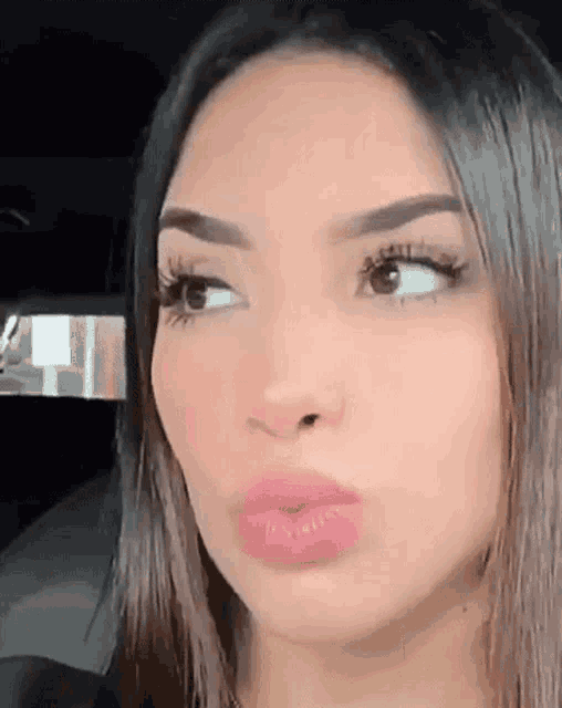 a close up of a woman 's face while sitting in a car making a funny face .