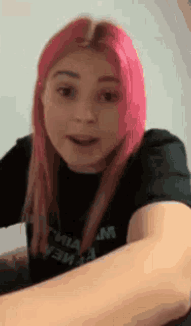 a girl with pink hair is wearing a black t-shirt .