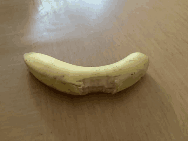 a banana that has been cut in half sits on a wooden surface