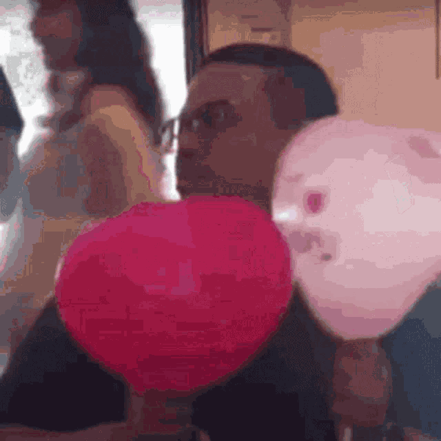 a man is holding a pink heart shaped balloon in his hand