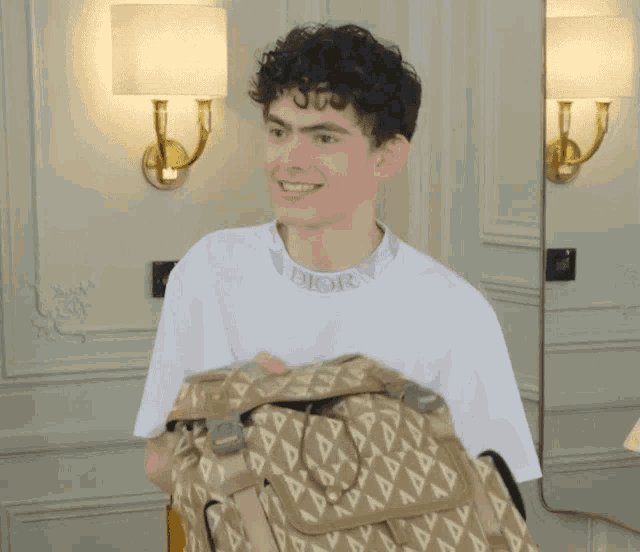 a man wearing a dior t-shirt holds a bag