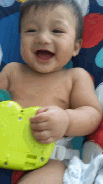 a baby laying on a blanket with a yellow toy