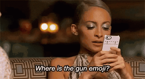 a woman is sitting on a couch looking at her cell phone and asking where is the gun emoji .
