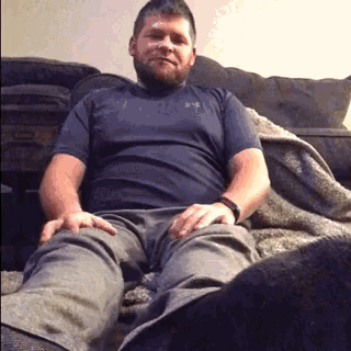 a man with a beard is sitting on a couch with his legs crossed