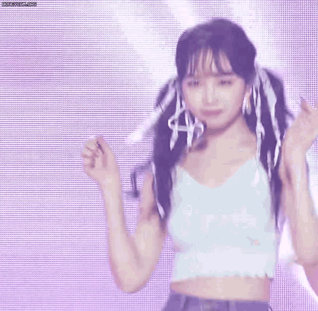 a woman is dancing on a stage wearing a crop top and jeans .