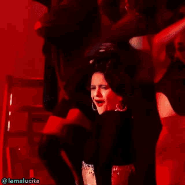 a woman in a black crop top is dancing on stage