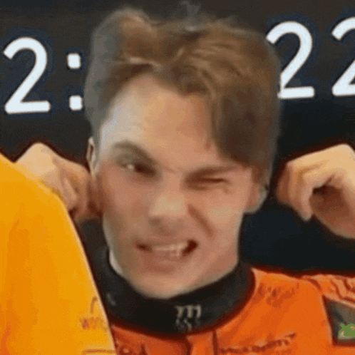 a young man is making a funny face while covering his ears .